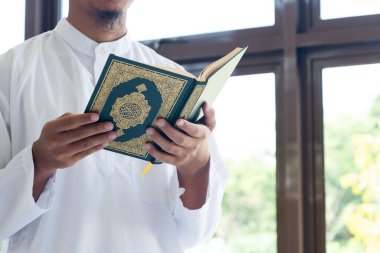 Müslüman adam Kuran okuyor. Kuran-ı Kerim 'in Arapça anlamı olan Kuran-ı Kerim