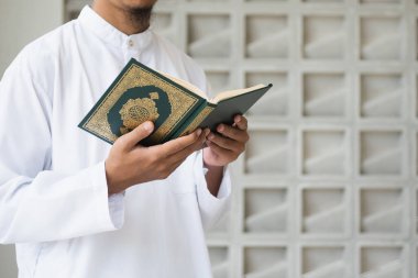 Müslüman adam Kuran okuyor. Kuran-ı Kerim 'in Arapça anlamı olan Kuran-ı Kerim