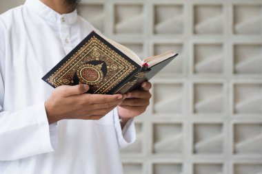 Müslüman adam Kuran okuyor. Kuran-ı Kerim 'in Arapça anlamı olan Kuran-ı Kerim
