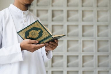 Müslüman adam Kuran okuyor. Kuran-ı Kerim 'in Arapça anlamı olan Kuran-ı Kerim