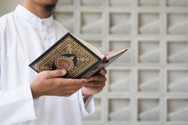 Müslüman adam Kuran okuyor. Kuran-ı Kerim 'in Arapça anlamı olan Kuran-ı Kerim