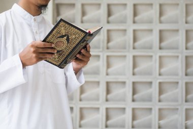 Müslüman adam Kuran okuyor. Kuran-ı Kerim 'in Arapça anlamı olan Kuran-ı Kerim