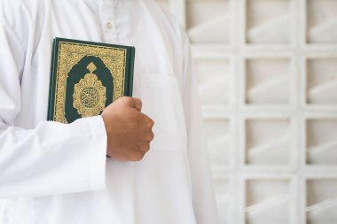 Kutsal Kur 'an' ın Arapça el yazısı ile yazılmış anlamı. Müslüman adam kutsal Kur 'an' ı tutuyor. İslami kavram