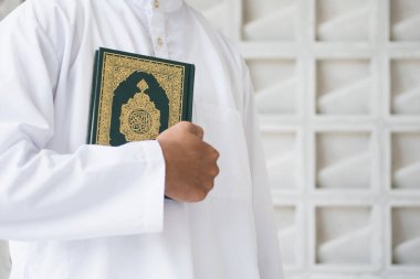 Kutsal Kur 'an' ın Arapça el yazısı ile yazılmış anlamı. Müslüman adam kutsal Kur 'an' ı tutuyor. İslami kavram
