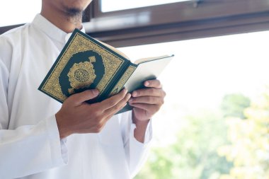 Müslüman adam Kuran okuyor. Kuran-ı Kerim 'in Arapça anlamı olan Kuran-ı Kerim