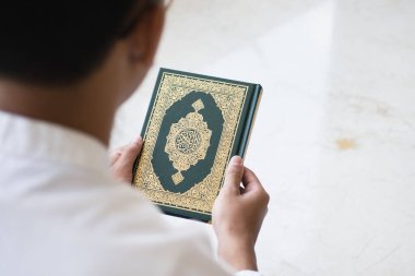 Kutsal Kur 'an' ın Arapça el yazısı ile yazılmış anlamı. Müslüman adam kutsal Kur 'an' ı tutuyor. İslami kavram