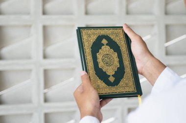 Kutsal Kur 'an' ın Arapça el yazısı ile yazılmış anlamı. Müslüman adam kutsal Kur 'an' ı tutuyor. İslami kavram