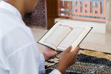 Müslüman adam Kuran okuyor. Kuran-ı Kerim 'in Arapça anlamı olan Kuran-ı Kerim