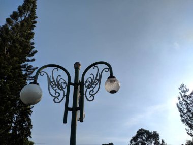 Arka planda bahçe lambaları olan bir sokak lambası..