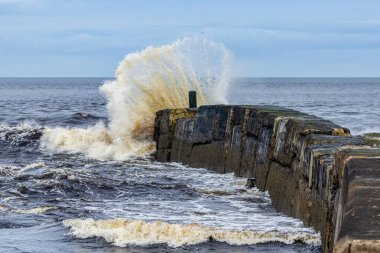 Deniz kıyısı manzarası, dalgalar iskeleye çarpıyor.