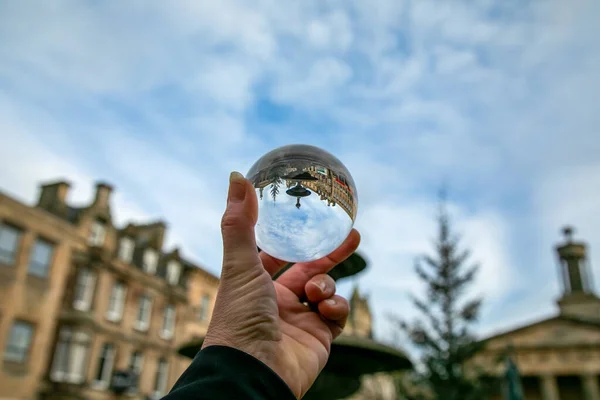 photography glass ball in human hand taking urban shots towards the town and the sky with blue and white clouds