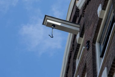 Geleneksel, tarihi Amsterdam şehir evleri, kanalların kıyısında, kantilleri ve kancaları olan, ilkbaharda dar eğimli, güzel mavi gökyüzü olan evlerin ön köşelerinde.