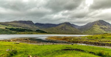 Munro Dağı 'nın manzarası Blaven İskoçya' da bir göl boyunca zirvenin tepesinde bulut var.