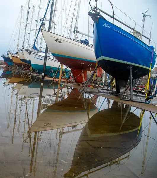 Yağmurdan sonra su birikintilerindeki doğal yansımalarla limandan ayrılan tekneler.