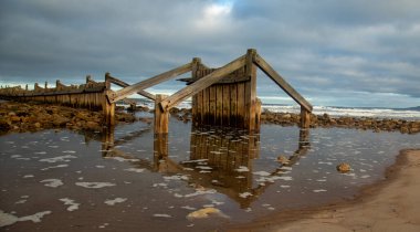 Dalgalar çekildikçe doğal su yansıması olan plajda kurumuş bir yapı.