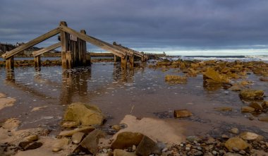 Dalgalar çekildikçe doğal su yansıması olan plajda kurumuş bir yapı.