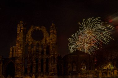 Şenlik ateşinde Elgin Katedrali 'nin üzerindeki karanlık gökyüzünde havai fişekler.