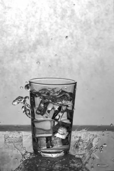 Stock image glass beaker with water and ice with splashes of water