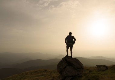 Gün batımında kayadaki bir adamın silueti.