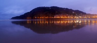 Ulia Dağı ve Zurriola Sahili. Ula Dağı ve şehrin ışıkları güneş doğarken Zurriola plajına yansıdı, Donostia San Sebastian, Euskadi
