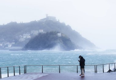 Weather in Donostia. People with bad weather on the coast of Donostia - San Sebastian, Euskadi clipart