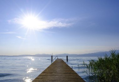 Garda Gölü 'nün üzerindeki günbatımı, bir iskeleden görünen gökyüzünü resmediyor, İtalya' da unutulmaz bir kartpostal manzarası yaratıyor..