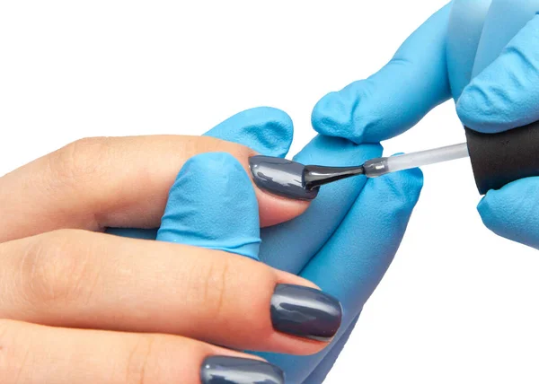 Manikür ve mavi ojeli bir kadın elinin beyaz arka plandaki güzellik salonundaki yakın çekimi.