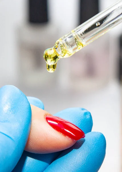 Modern bir laboratuvarda manikür ve kadın elleri, manikür üstüne manikür yağları dökülür.
