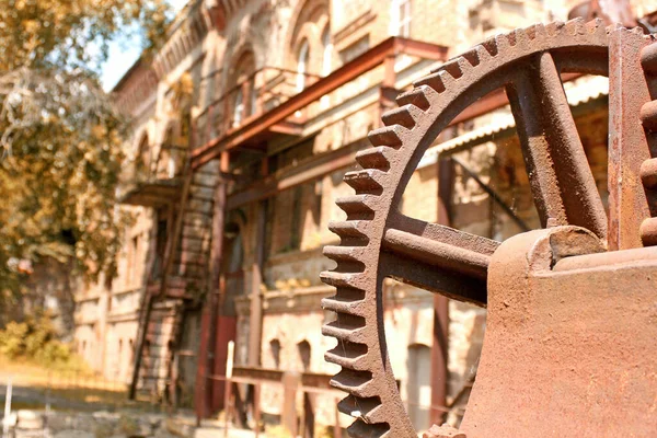 Eski sanayi binasının arka planında paslı dişliler