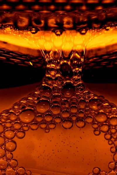beer bubbles while beer being poured into beer goblet in a bar macro photography
