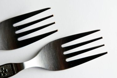 Yan yana yerleştirilmiş gümüş çatal çatal seti beyaz arka plan makro yakın çekim fotoğrafına izole edilmiş.