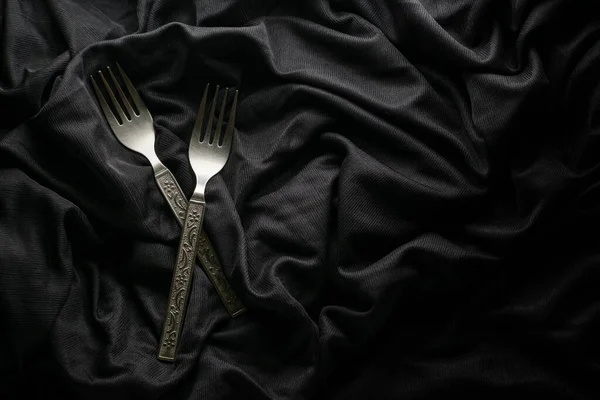 couple of German silver fork place on a black velvet cloth mood object photography