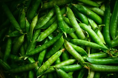 Kabuklarındaki taze taze bezelyelerin yakın plan görüntüsü canlı bir doğal doku yaratıyor ve sağlıklı beslenmeyi ön plana çıkarıyor. Organik gıda, tazelik ve sağlıklı yaşam tarzları için ideal bir tema..