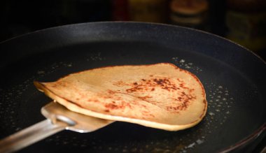 Kızartma tavasında altın bir gözleme çeviriliyor. Yemek pişirme teknikleri, doku ve iştah açıcı görünüme odaklı lezzetli bir kahvaltı hazırlığı sergileniyor..