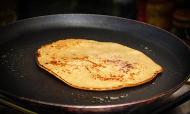 Siyah yapışmaz bir tavada cızırdayan kahverengi bir gözlemenin yakın çekimi kahvaltı hazırlıklarını vurguluyor..