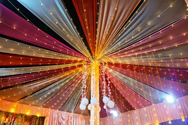 Renkli ışıklar ve süslemelerle süslenmiş şenlikli tavan, kutlamalara uygun canlı bir ortam yaratıyor. Işığın ve kumaşın etkileşimi neşeli ve davetkar bir ruh hali yaratır..