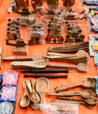 Portakal rengi bir bezde bulunan çeşitli ahşap mutfak aletleri ve dekoratif eşyalar koleksiyonu. El yapımı bu güzel objelerde geleneksel sanat, fonksiyonel tasarım ve kültürel estetiği vurguluyor..