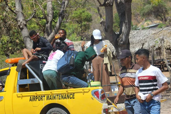 Atambua, Doğu Nusa Tenggara - 18 Ağustos 2022: çanta, hoparlör ve içki gibi ekipmanları taşıyan havalimanı bakım araçlarını kullanan turist grupları
