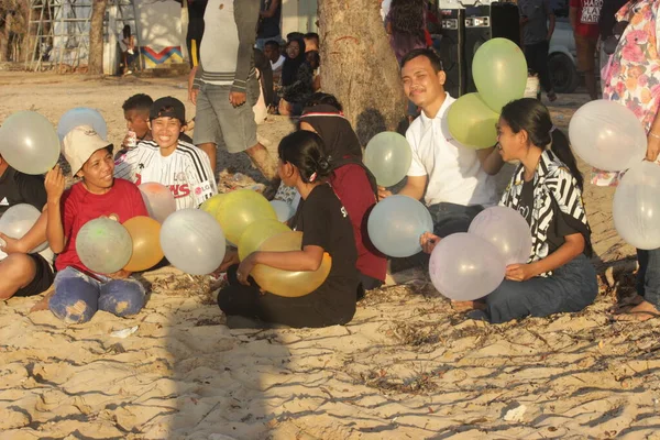 2022年8月18日 东努沙登加拉的阿坦布阿 坐在一棵树下的白色沙滩上 手持几个色彩艳丽的气球的游客暴露在阳光下 — 图库照片