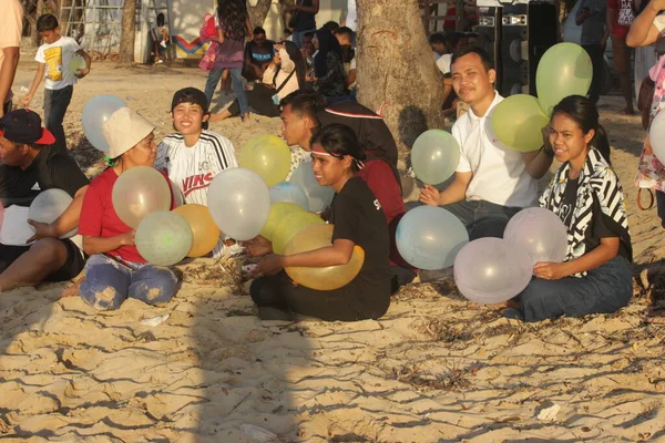 2022年8月18日 东努沙登加拉的阿坦布阿 坐在一棵树下的白色沙滩上 手持几个色彩艳丽的气球的游客暴露在阳光下 — 图库照片
