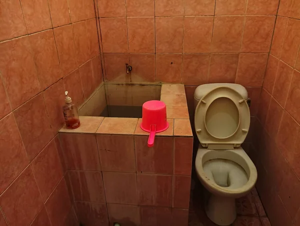 Atambua, Doğu Nusa Tenggara - 26 Mart 2023: bir banyo küveti, musluk, sıvı sabun, dipper ve beyaz sifon tuvaletinden oluşan banyo içi