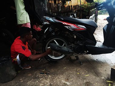 Atambua, Doğu Nusa Tenggara - 7 Nisan 2023: Motosiklet tamirhanesinde birkaç motosiklet tamircisi tarafından bakım yapılıyor