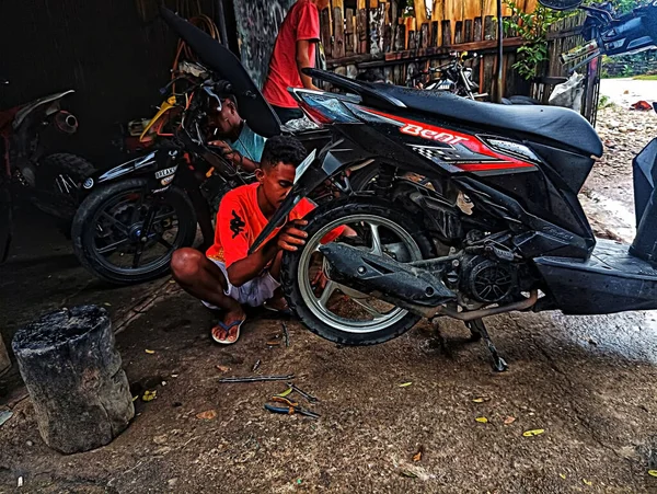 Atambua, Doğu Nusa Tenggara - 7 Nisan 2023: Motosiklet tamirhanesinde birkaç motosiklet tamircisi tarafından bakım yapılıyor