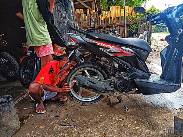 Atambua, Doğu Nusa Tenggara - 7 Nisan 2023: Motosiklet tamirhanesinde birkaç motosiklet tamircisi tarafından bakım yapılıyor