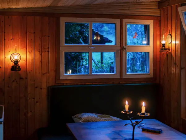 Candles burn in front of the window in the cozy garden hut