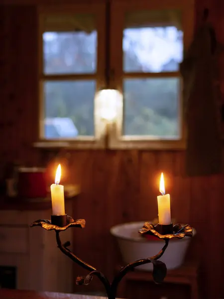 Candles burn in front of the window in the cozy garden hut