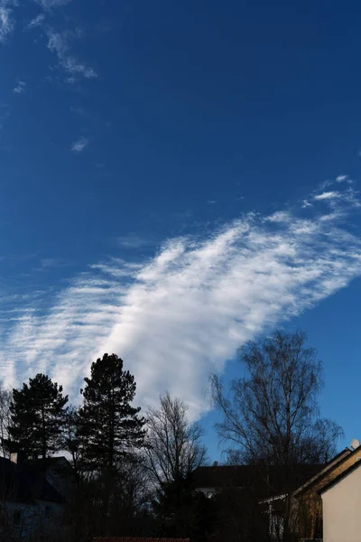 Strange cloud formation with torn clouds over tree and house