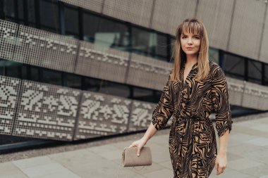 Elinde yapraklar olan bir kadın, parkta duruyor.