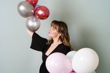 Genç Kadın Gri Arkaplana Karşı El Balonlarıyla Poz Veriyor ve Tutuyor