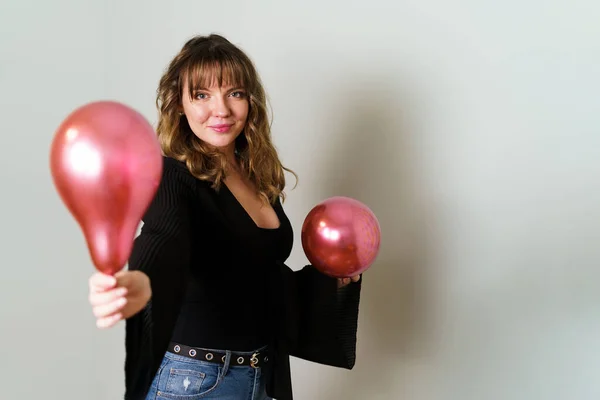 Genç Kadın Gri Arkaplan Karşısında Pembe Balon Veriyor